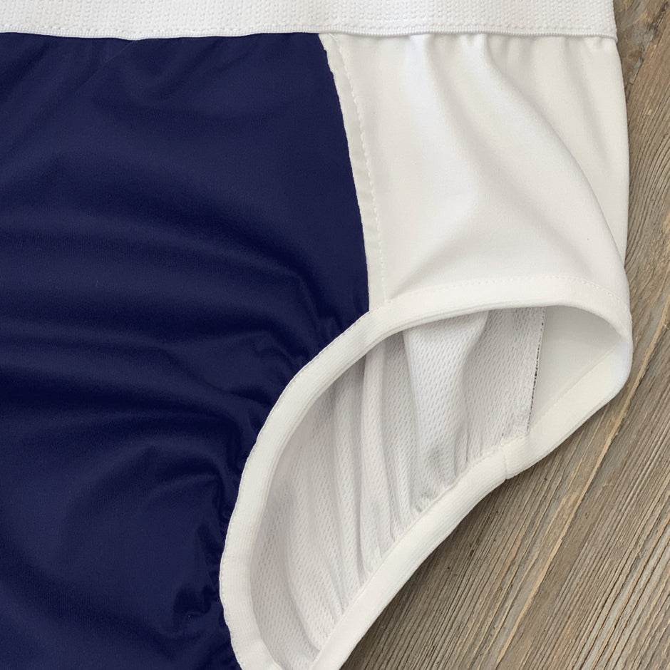 Close-up of the ThreadedArmor The Basic Brief, Light Absorbency, featuring navy and white color blocks, smooth fabric with visible stitching, and elastic at the leg opening—designed for discreet leak protection.