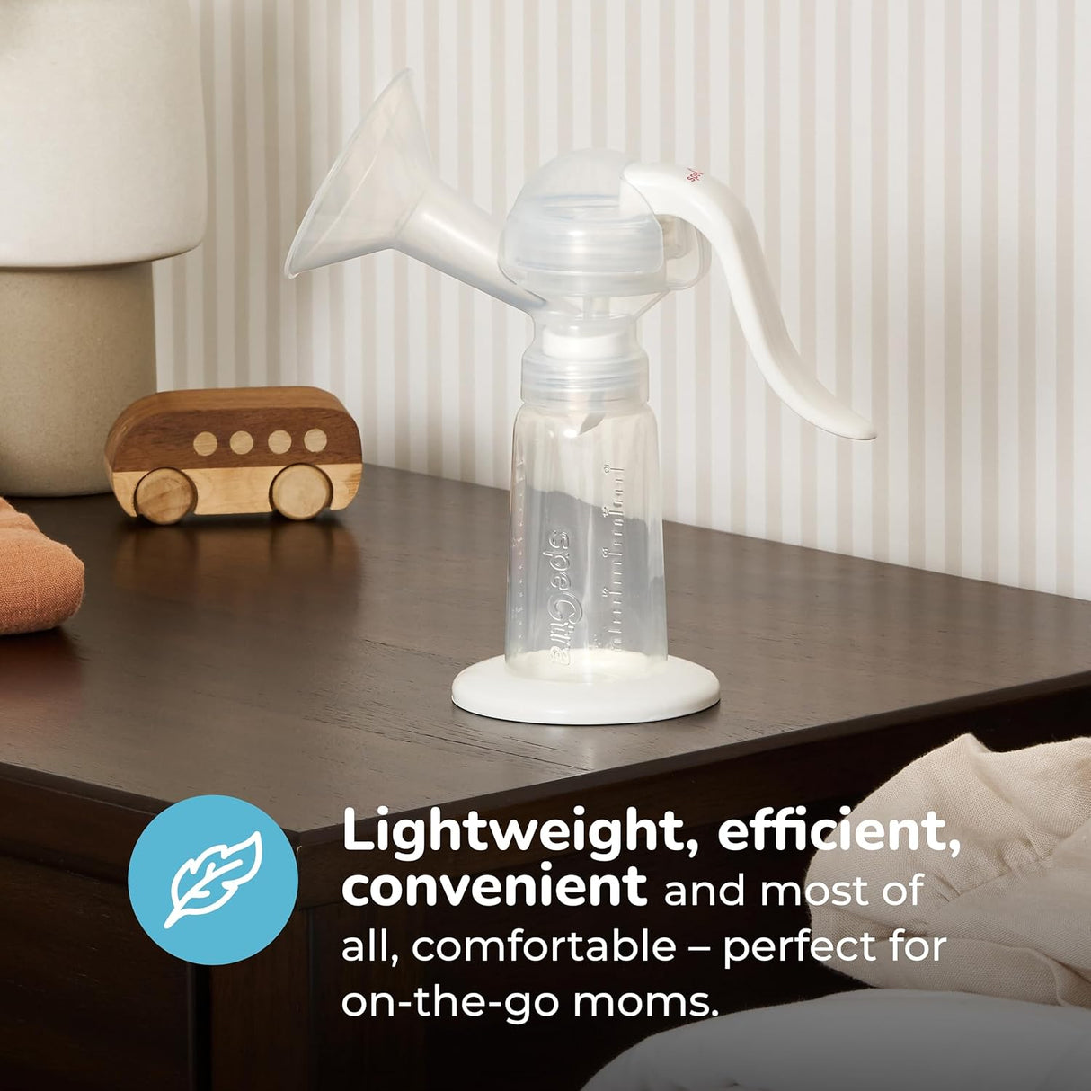 The Spectra Handy Plus Manual Breast Pump by Spectra rests on a wooden nightstand beside a toy car, showcasing its lightweight, efficient, and comfortable design—perfect for on-the-go moms who value convenience and portability.