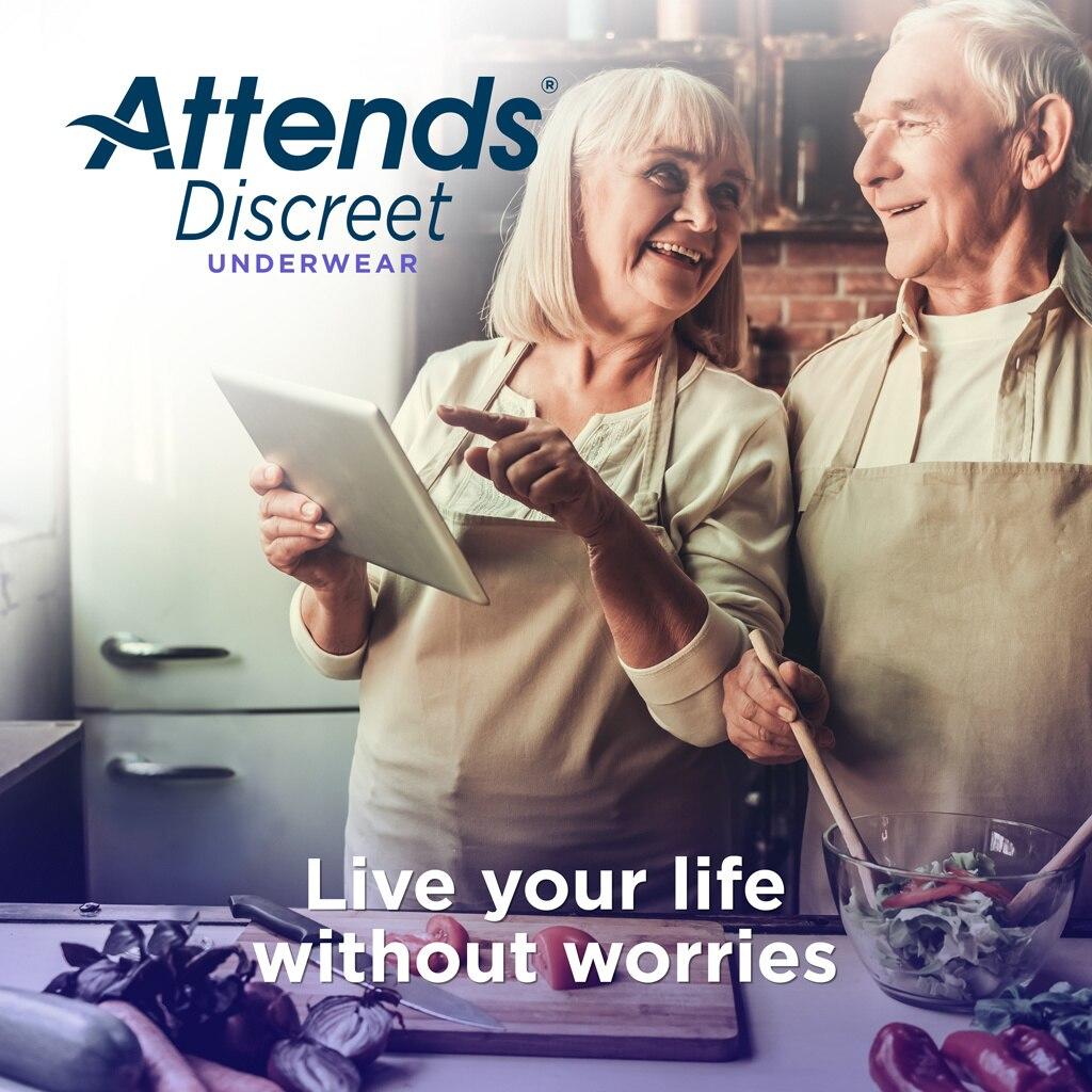 Two older adults wearing aprons smile as they prepare food in a kitchen. The woman holds a tablet. Text: Attends Discreet Womens Underwear from Attends offers moderate absorbency—enjoy worry-free moments with discreet incontinence protection.