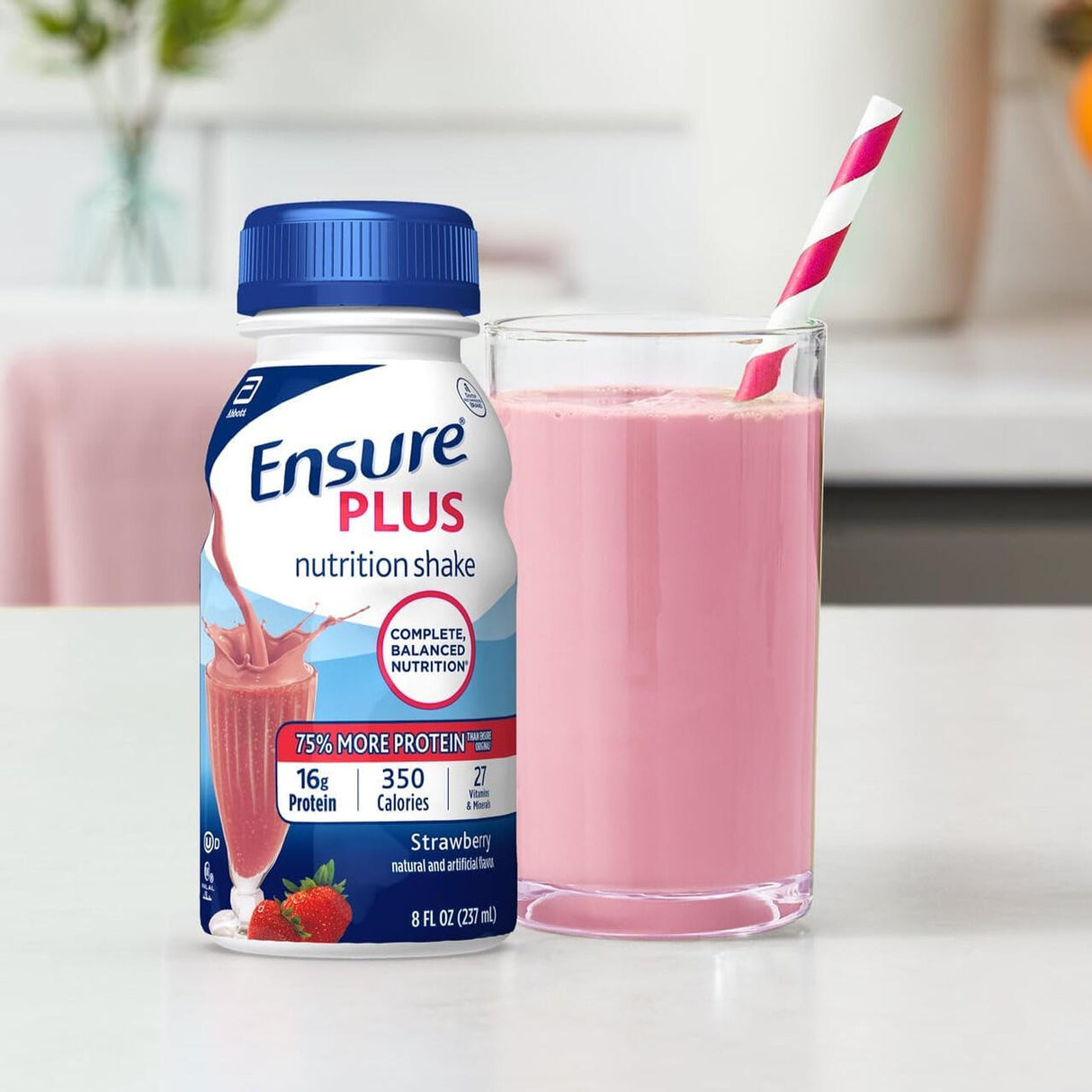 An 8 oz bottle of Ensure Plus Nutritional Shake, Strawberry by Abbott Nutrition (CS/24), stands beside a glass filled with the pink shake and a pink-striped straw on a light kitchen counter.