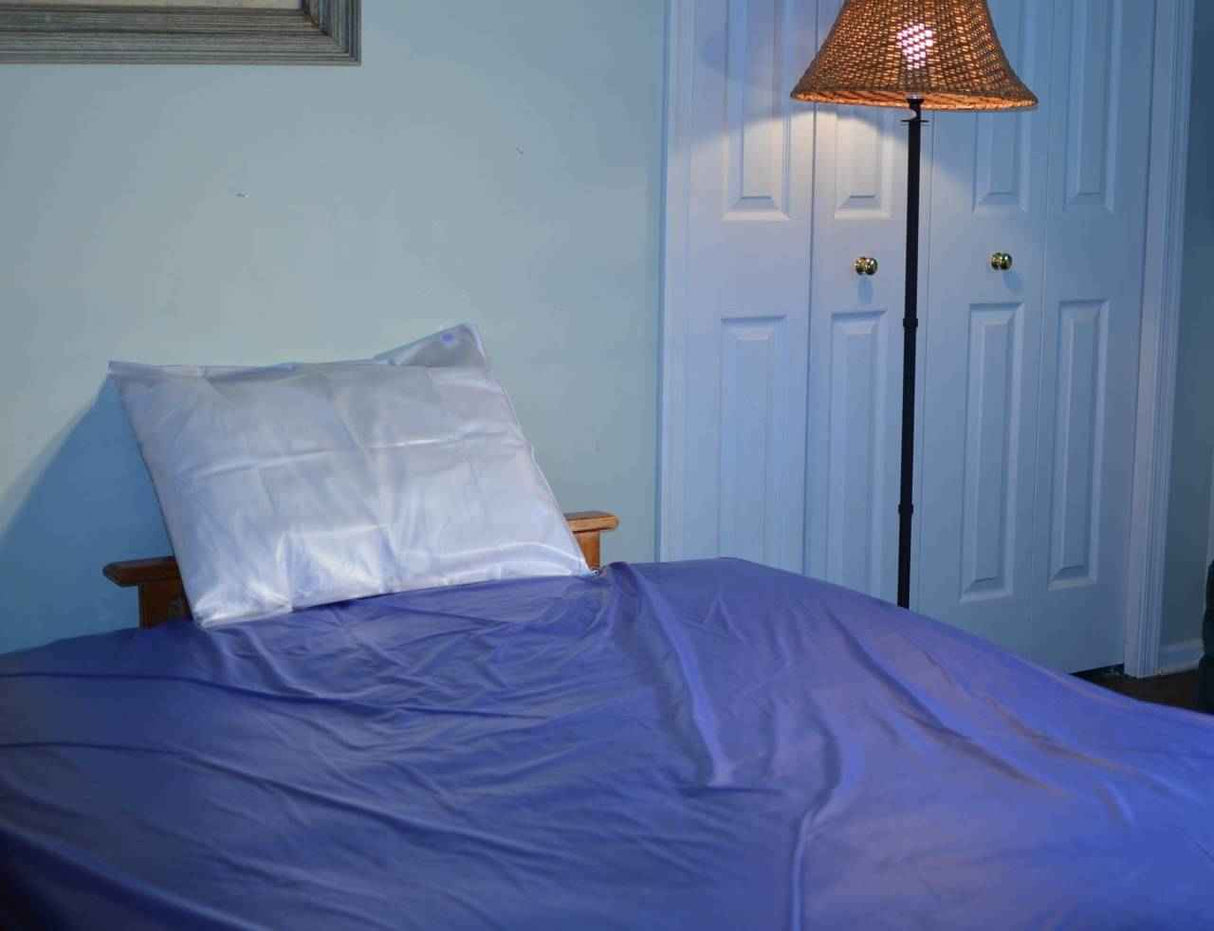 A neatly made bed with a blue sheet, white pillow, and Gary Heavy Duty Plastic Mattress Cover Protector (Twin) sits by a tall floor lamp with a woven shade near white double closet doors in a softly lit room.