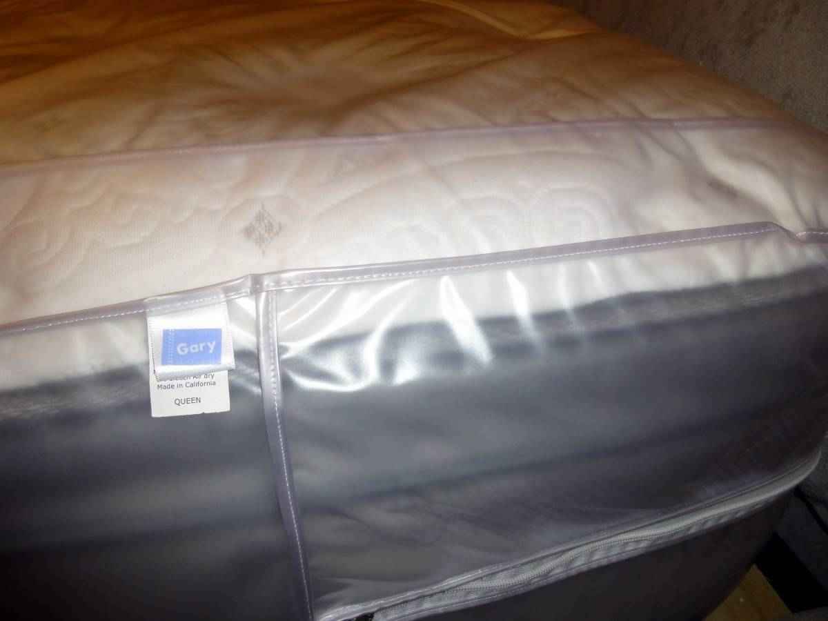 A close-up of a mattress corner covered with the Gary Heavy Duty Plastic Mattress Cover Protector, Twin. A small label displays Gary in blue and white text.
