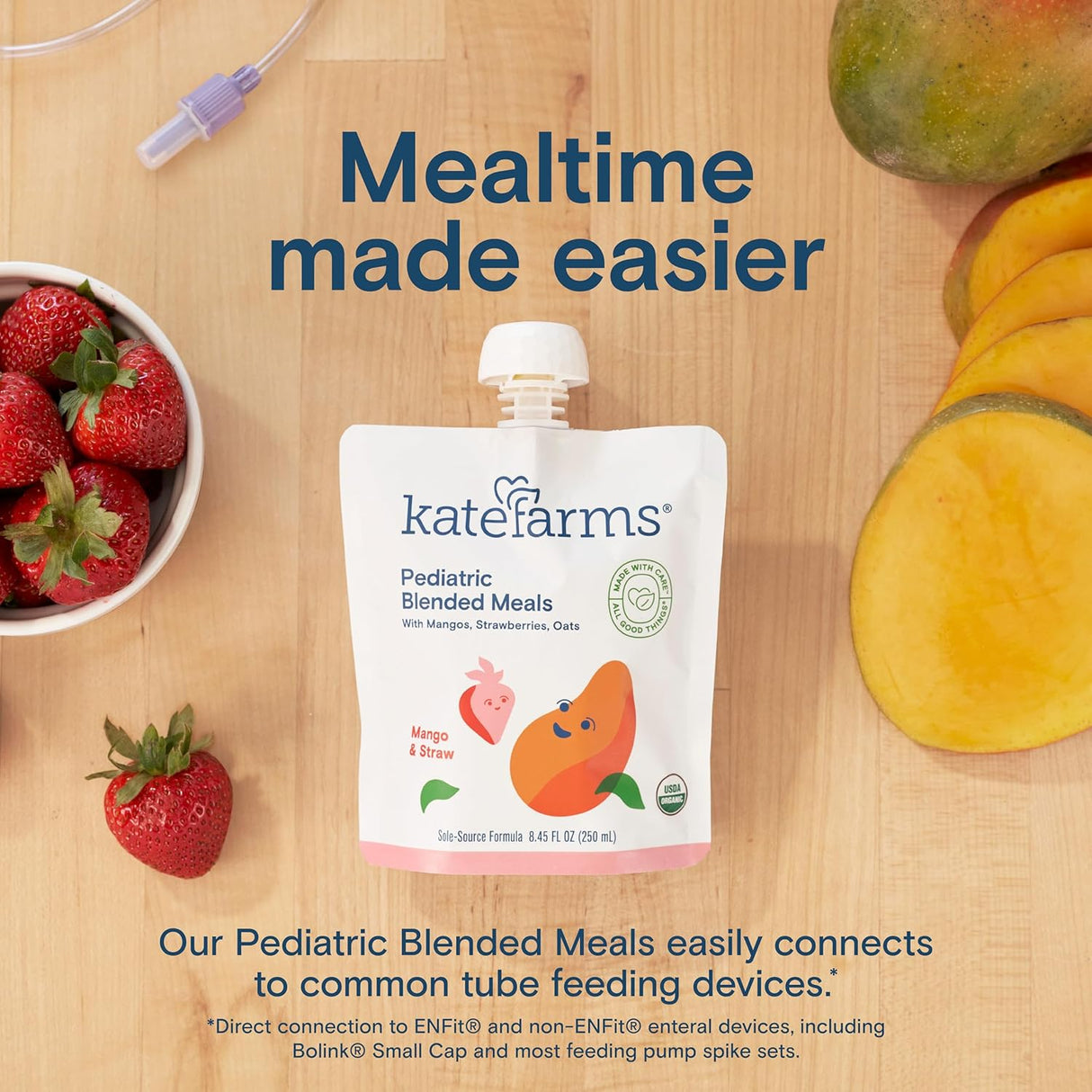 Kate Farms Pediatric Blended Meals, Mango & Strawberry, CS/12 is displayed on a wooden table with fresh strawberries, a mango, syringe, and tubing. Above, the text says: Mealtime made easier with plant-based nutrition from Kate Farms.