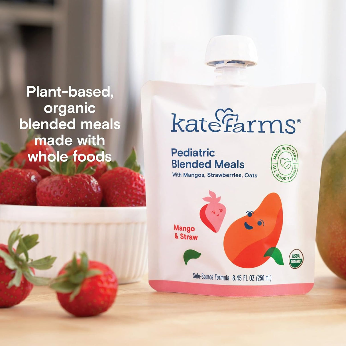 A pouch of Kate Farms Pediatric Blended Meals, Mango & Strawberry, CS/12 sits on a table beside fresh fruit. The Kate Farms package highlights its organic, plant-based nutrition made with whole foods.