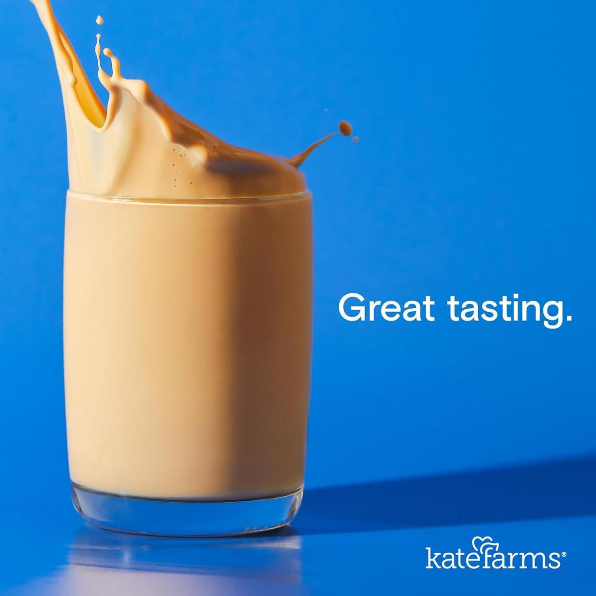 A glass of creamy, light brown Kate Farms Standard Formula 1.0, Plain, Case/12 splashes against a bright blue background. White text reads Great tasting. The Kate Farms logo appears in the bottom right corner.