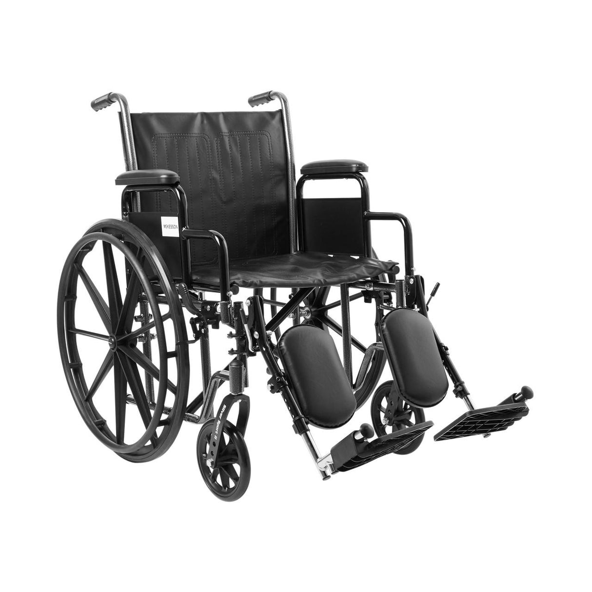 The McKesson Standard 20 Wheelchair features elevating swing-away footrests, detachable desk arms, and large rear wheels. Shown in black steel with padded leg supports against a plain white background.