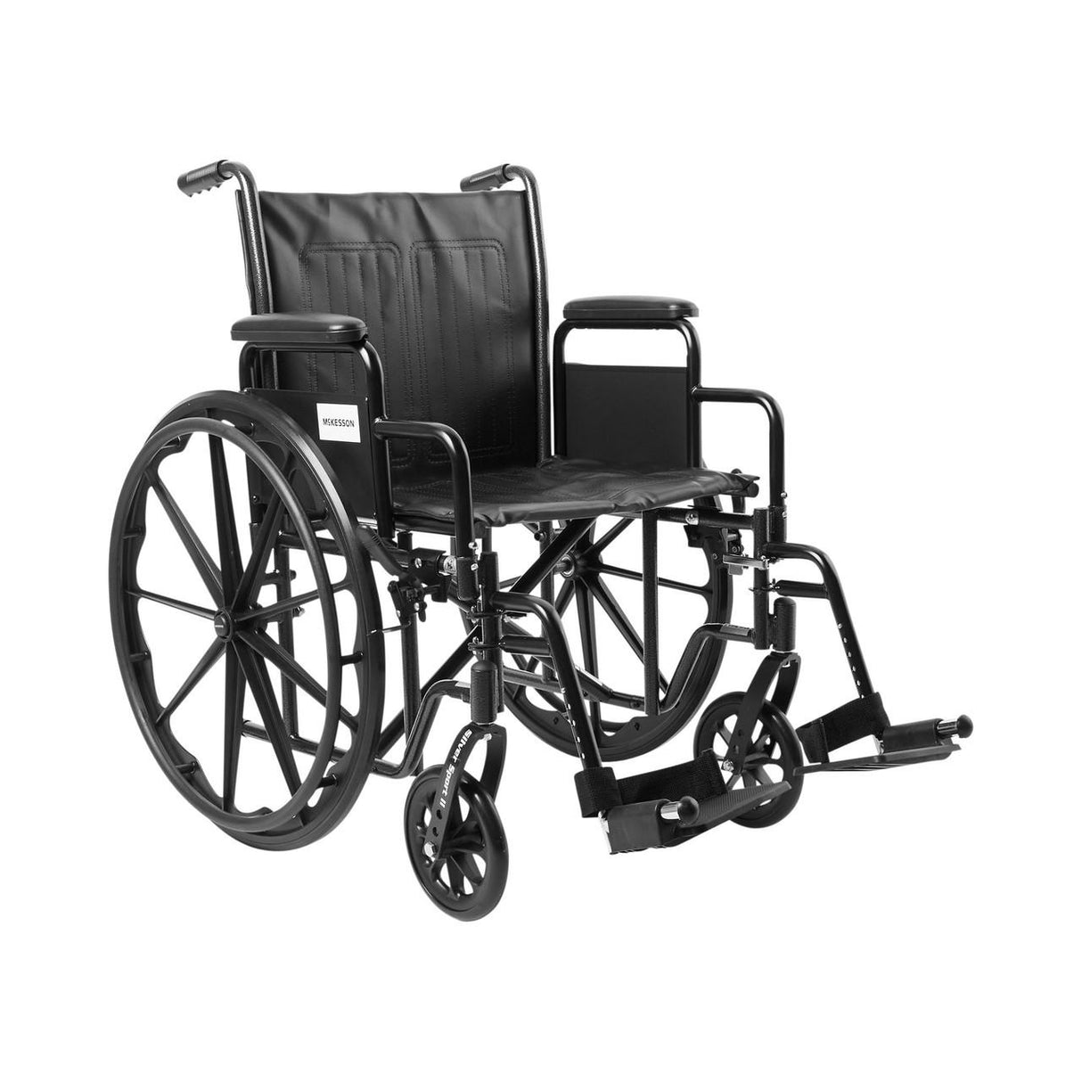 The McKesson Standard 20 Wheelchair features swing-away footrests, detachable desk arms, and a cushioned seat and backrest. Shown in black carbon steel with large rear wheels, small front wheels, and displayed against a plain white background.