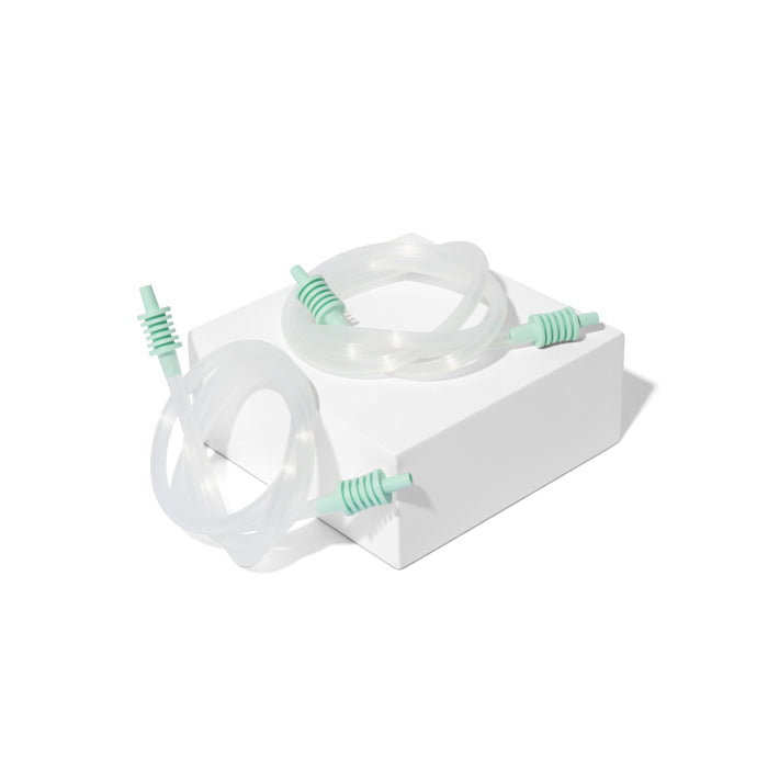 A transparent medical tube with green connectors, compatible with the Motif Twist Double Electric Breast Pump by Motif, is coiled atop a white rectangular box against a plain white background.