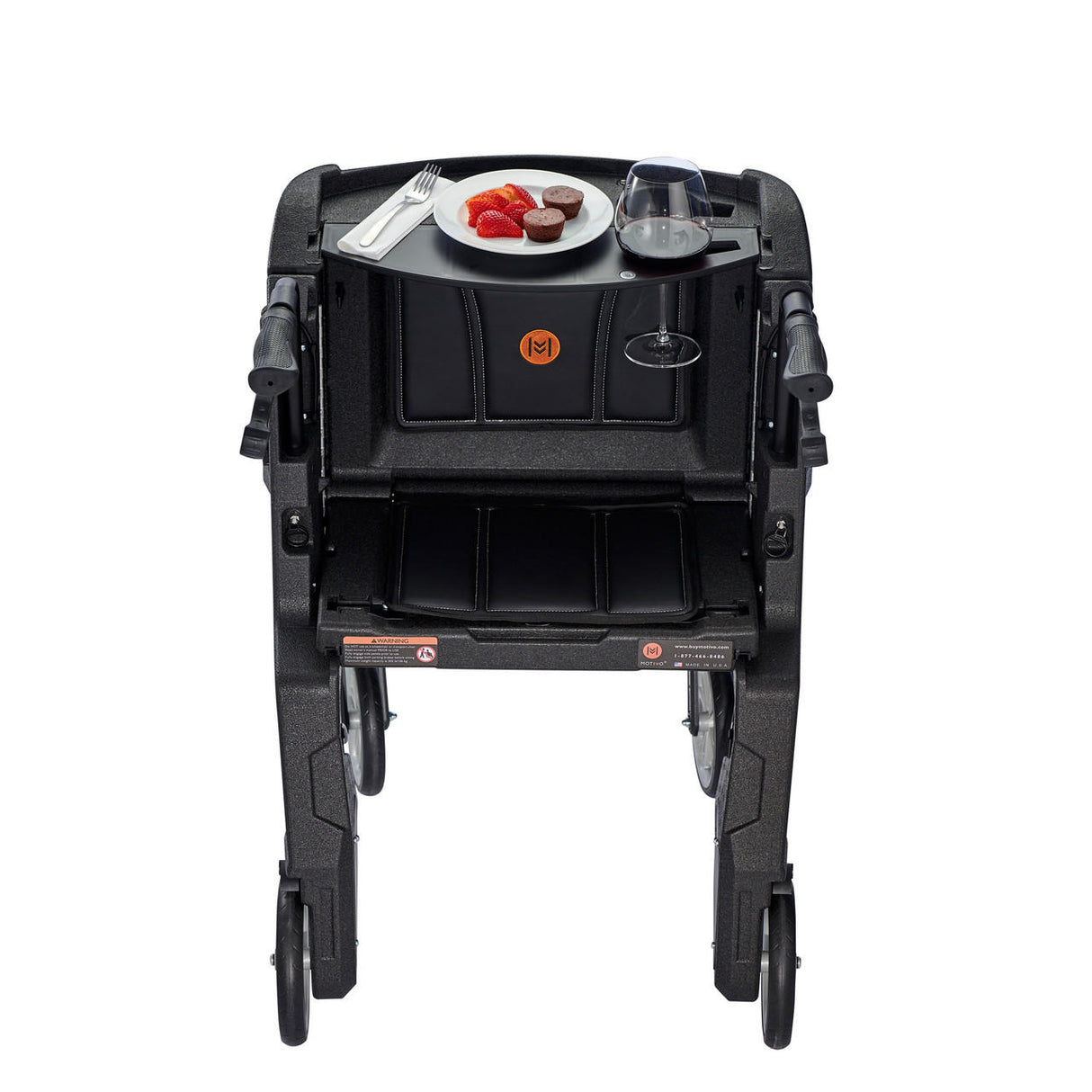 The Motivo Tour Rolling Walker with Seat, Backrest, and Storage by Motivo displays strawberries, chocolates, a fork, and a glass of wine on its built-in tray—a stylish upright rollator offering practical support and convenience.