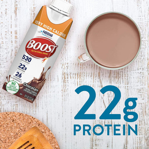 A Nestle Boost Very High Calorie (VHC), Chocolate, 8 oz carton from Nestle Nutrition is shown beside a cup of chocolate beverage on a white wooden surface. Text states 22g Protein in large blue letters.