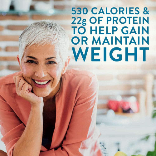Smiling woman with short gray hair in a peach top leans on a counter. Text: 530 calories & 22g protein—Nestle Boost Very High Calorie (VHC), Strawberry, 8 oz, by Nestle Nutrition, is a high calorie supplement for weight gain or maintenance.