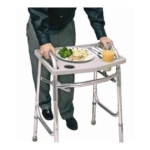 A person using the Jobar North American Health + Wellness Walker Tray stands behind their walker, the tray holding a plate of food, broccoli, and a glass of juice. The person wears gray pants and a black shirt.