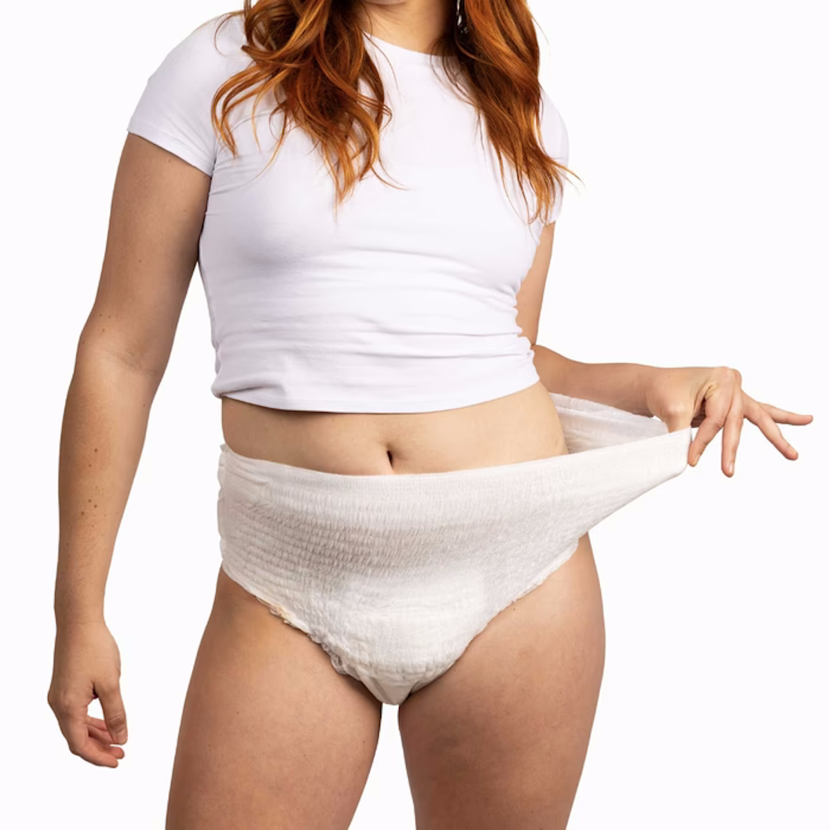 A woman in a white crop top shows the stretch and comfort of NorthShore GoSupreme Lite Pull-On Underwear by pulling the waistband outward, highlighting their reliable leak protection and easy-to-wear design.