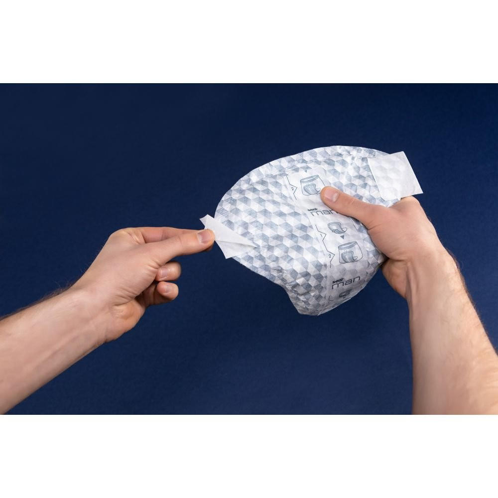 In front of a dark blue background, someone peels a white strip from a small, padded mailer with a textured, bubble-like exterior—possibly revealing Seni Man Active Guards by Seni for light absorbency.