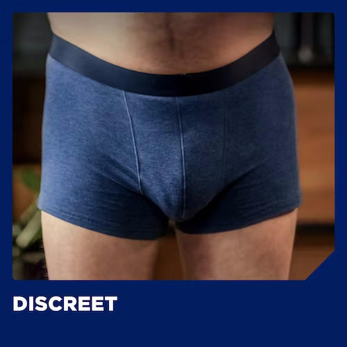 A man wears blue boxer briefs with a black waistband. DISCREET appears in bold white letters at the bottom left, emphasizing comfort and protection—perfect for pairing with TENA for Men Guards, Maximum by TENA.