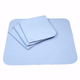 Four NorthShore Champion XD Washable Underpads by NorthShore, in light blue, are shown with three folded on one fully opened pad over a white background. These waterproof bed protectors deliver reliable absorbency and protection.