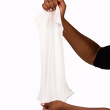 A person with medium-dark skin holds a large, white NorthShore Supreme Quilted Cleansing Wipe between both hands against a plain white background.
